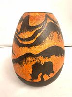 Front view of orange and black signed pottery vase
