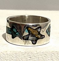 Front view of silver band ring showing star-shaped turquoise, red coral, abalone inlay