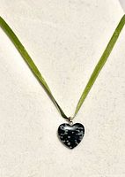 Heart shaped snowflake obsidian pendant on green ribbon necklace displayed against neutral background