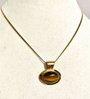 Front view of necklace on bust displaying tiger’s eye pendant