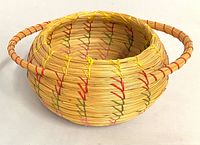 Angled view of sweetgrass basket showing handle and exterior colored stitching