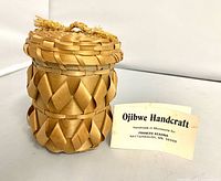 Front view of lidded black ash basket with maker’s card