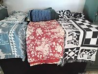 Stacked throws showing cow tapestry, quilted floral throw and crocheted afghan