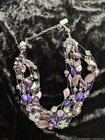 Entire necklace displayed on black fabric showing multi strands and clasp