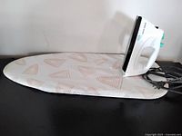 Steam iron resting on covered tabletop ironing board