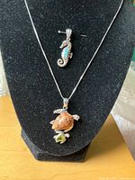 Entire lot on display bust showing necklace with sea-turtle pendant and separate seahorse pendant
