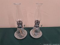 Full view of both clear glass oil lamps