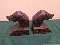 Front view of both carved wooden dog head bookends on table