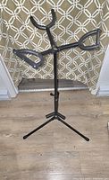 Full view of black foldable triple guitar stand set up