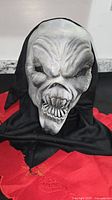 Front view of grey skull mask with black hood
