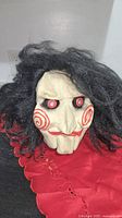 Front view of latex Billy the Puppet mask with hair and red collar