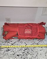 Rolled blanket with flap closure and carry strap on countertop, tape measure showing length
