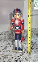 Front view of wooden Montreal Canadiens nutcracker with measuring tape showing height ~14.5 in
