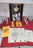 Lot overview showing signed print, jersey, and programs
