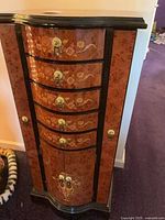 Front view of jewelry armoire showing drawers, doors, hardware and painted finish