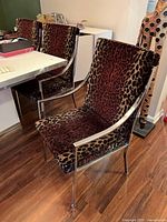Two chairs side view showing chrome arms, leopard upholstery