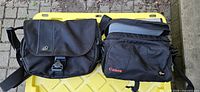 Two black nylon camera bags side by side on yellow crate