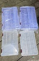 Four Plano clear organizer boxes on wooden surface; two in factory plastic wrap, two unwrapped