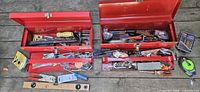 Two open red metal toolboxes with assorted tools and hardware visible; level, tape measure and pliers placed in front