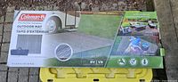 Full view of boxed Coleman outdoor mat showing product images and branding