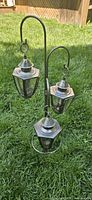 full view of metal stand with three lanterns set on grass