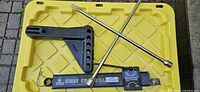All components laid out on yellow lid: sway bar, drop shank, lug wrench, hitch pin