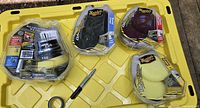 All items on yellow crate: three sealed pad packs (yellow, maroon, black) and adapter package