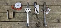 All three chrome wreath hangers with two ribbon rolls on wooden surface