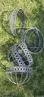 Six metal hanging planters stacked on grass