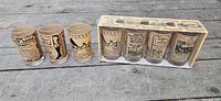 Full view of seven glasses, five in box, showing variety of advertisement prints