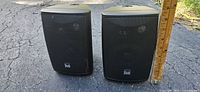 Dual black satellite speakers beside ruler