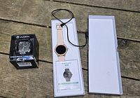 Overview of smartwatch in open box with charger, and boxed Ultimal case