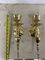 Pair of brass sconces beside tape showing 12 in length
