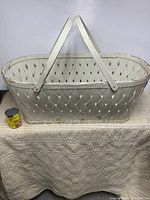 Front view of white wood splint hamper with handles and scale reference