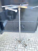 Full view of chrome four-arm garment rack with caster base