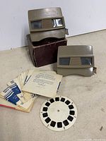 Two View-Master viewers, stack of paper reel sleeves, loose Bambi reel