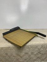 Overall view of wooden base guillotine paper cutter showing grid surface and cutting arm