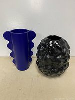 Blue wavy vase and black dimpled vase side by side