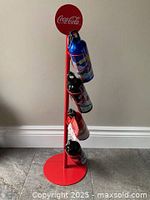 Full view of red Coca-Cola display stand with four Olympic water bottles attached