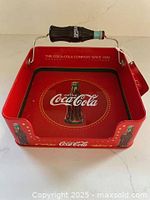 Angled view showing red metal holder, bottle handle, side graphics, hang tag