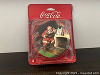 Front of sealed package showing Coca-Cola branding and Santa image on coaster