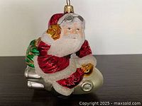 Front view of blown glass Santa riding rocket ornament