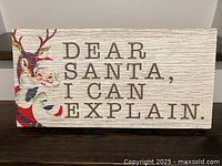 Front of wooden sign showing text and Santa illustration