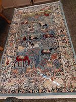 Full view of rectangular hunting scene rug showing pattern, size and border
