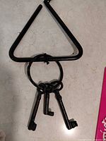 Front view of cast iron triangle with ring and three keys