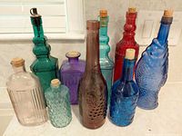 Group of nine colorful glass bottles on countertop