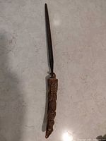 Full view of sharpening steel showing carved handle and metal rod