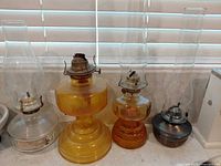 Group shot of four hurricane oil lamps with varying bases