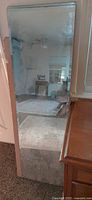 Tall frameless rectangular mirror leaning against wall