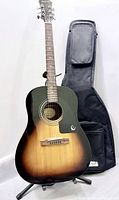 Front view of Epiphone AJ-100VS guitar on stand beside gig bag